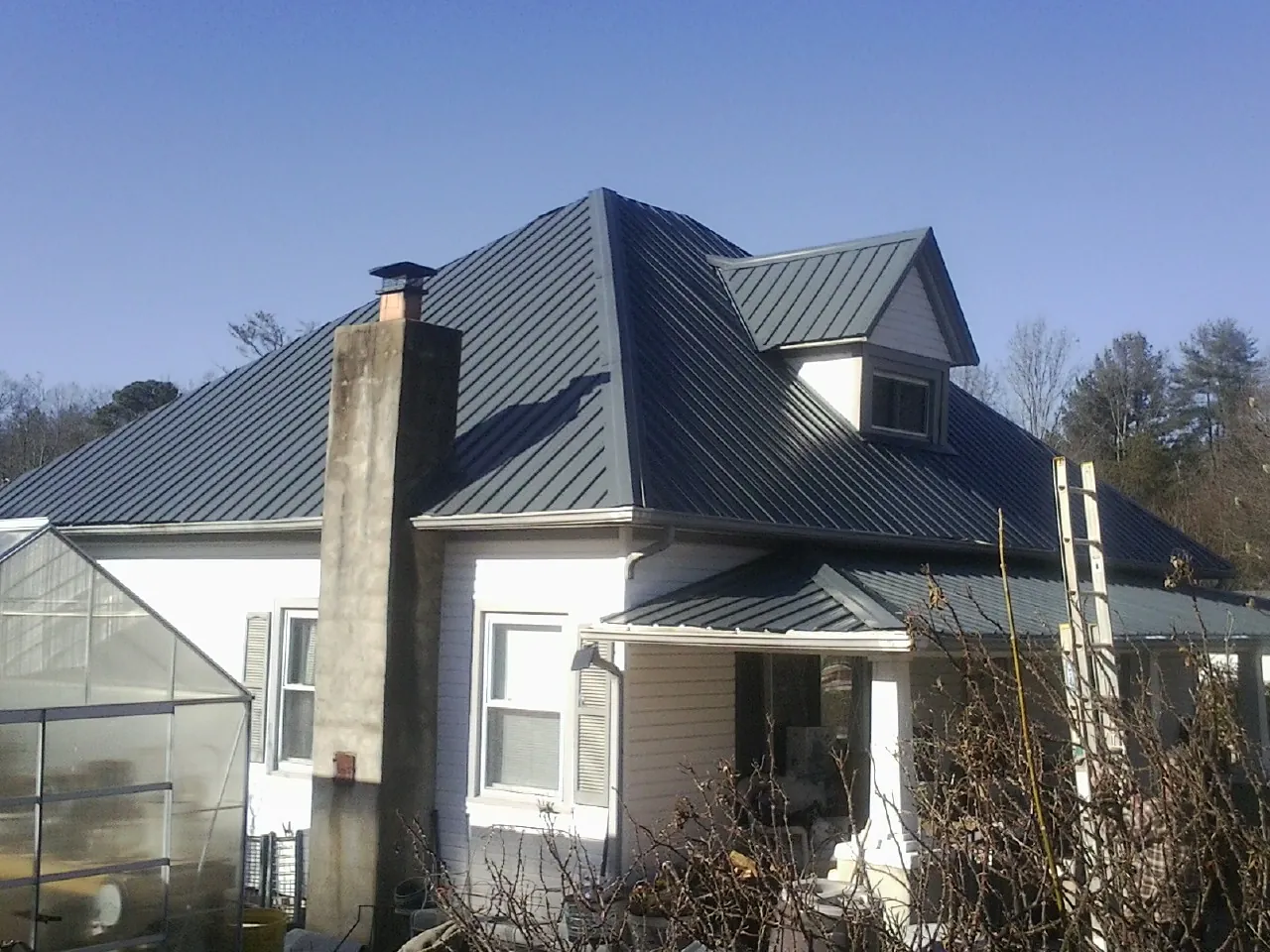 Dark blue standing seam metal roof on a white farmhouse with dormer — Slate & Tile Roof Repair by Roofing Brothers in Sparrows Point