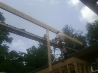 Carpenter setting a ridge beam over a new addition frame — Ice Dam Removal by Roofing Brothers in Sparrows Point