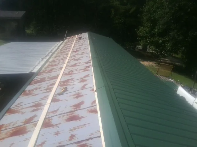 Old rusted panels beside newly installed green metal roofing — Wind Damage Roof Repair by Roofing Brothers in Sparrows Point