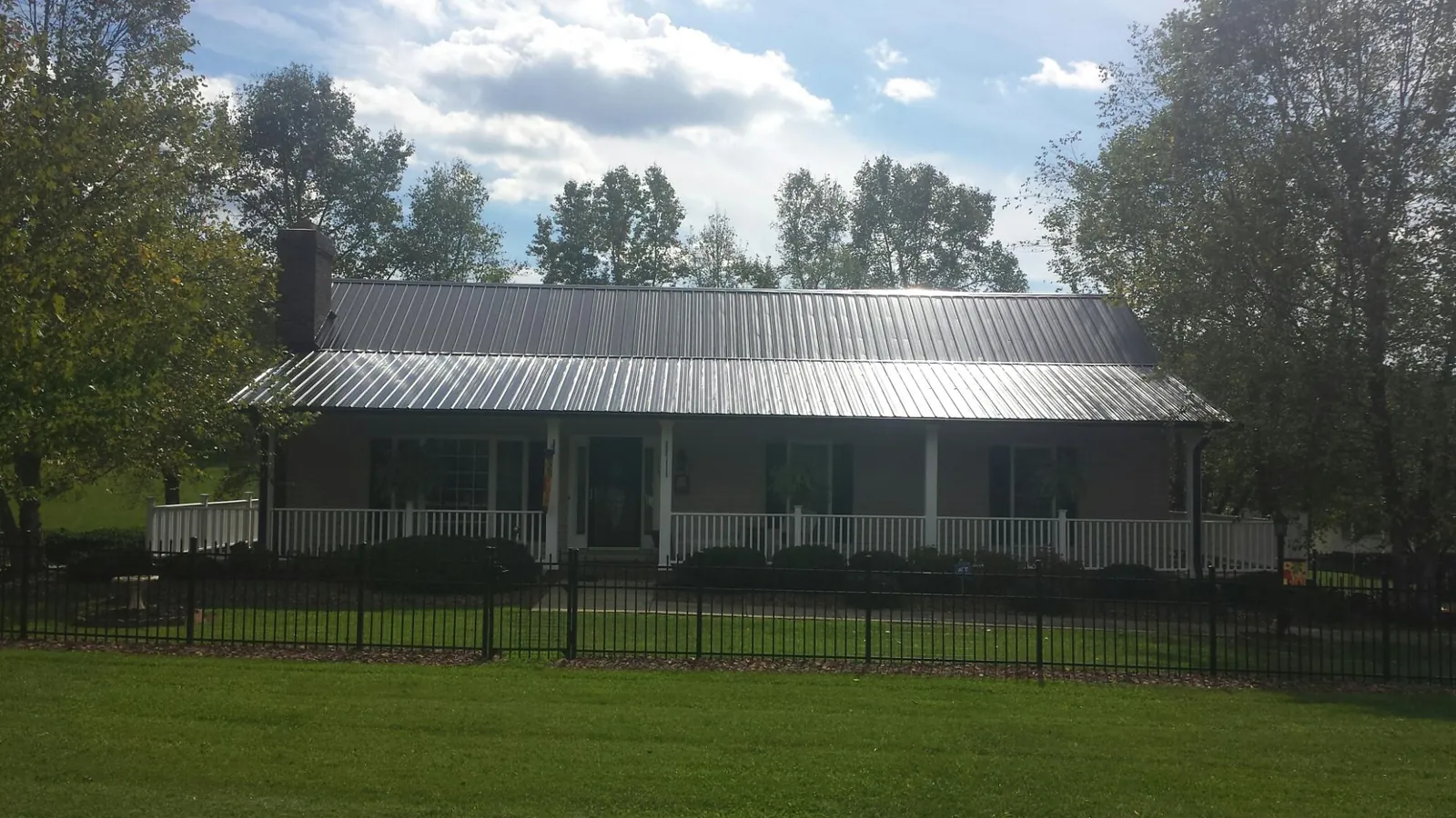 Gray metal roof on a brick ranch with a full width front porch — Gutter Guard Installation work by our crew in Sparrows Point