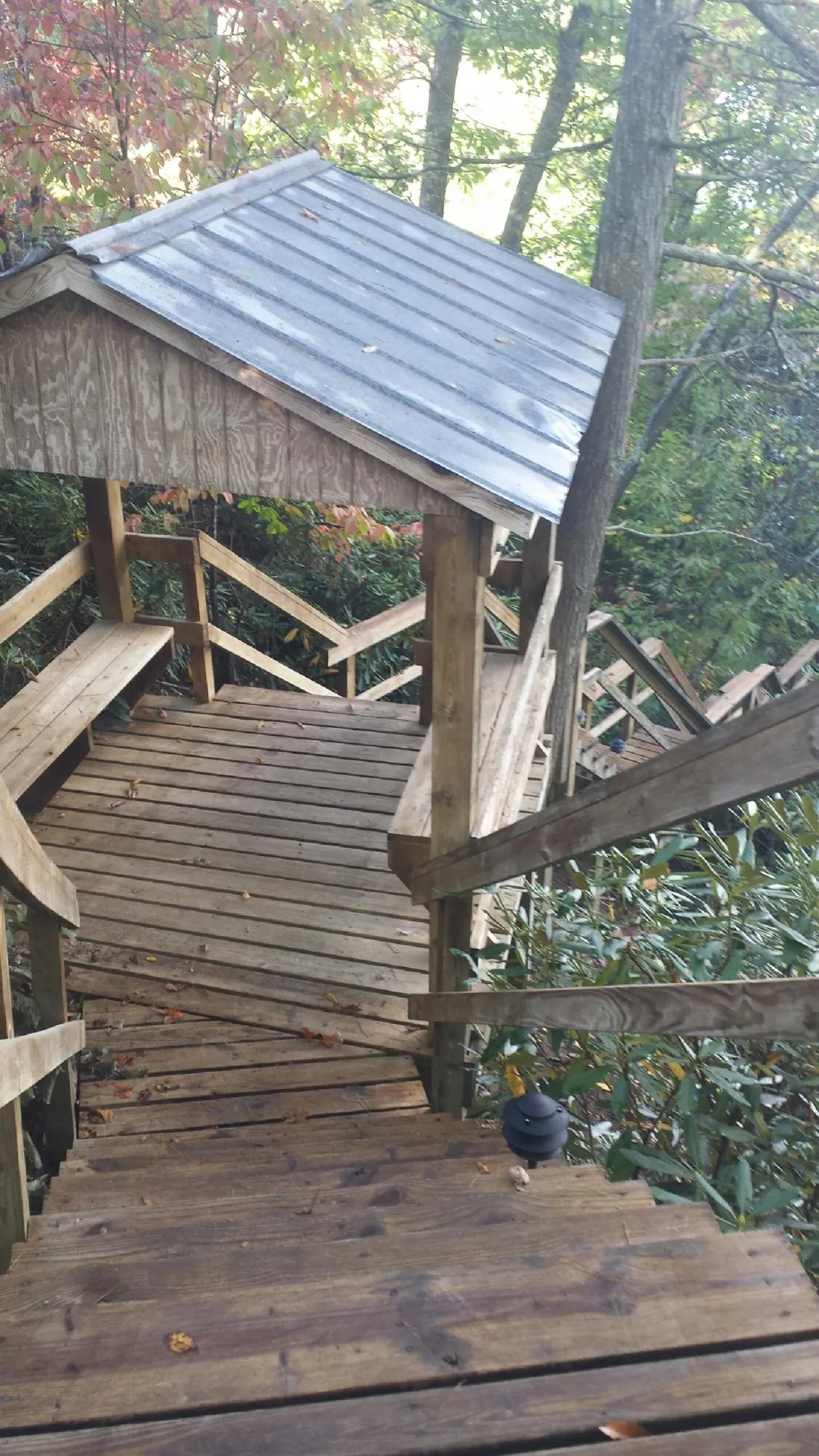 Metal roofed shelter over wooden steps on a wooded walkway — Skylight Repair & Installation work by our crew in Sparrows Point