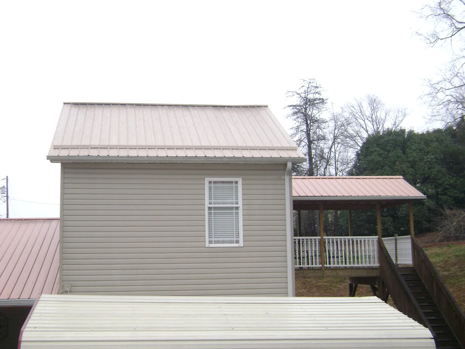Tan metal roofs on a two story addition and attached porch, from a Roof Replacement job in Sparrows Point