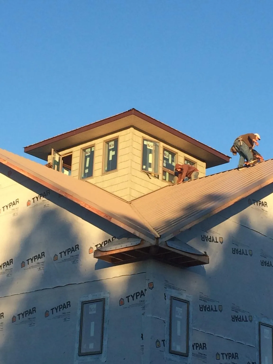 Roofers working around a rooftop cupola on a new metal roof at sunset — Roof Waterproofing in Sparrows Point by Roofing Brothers